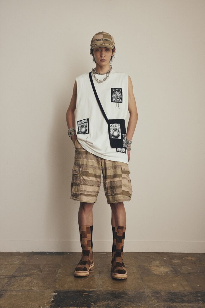 A relaxed white sleeveless tank-top with prints paired with beige cargo shorts.