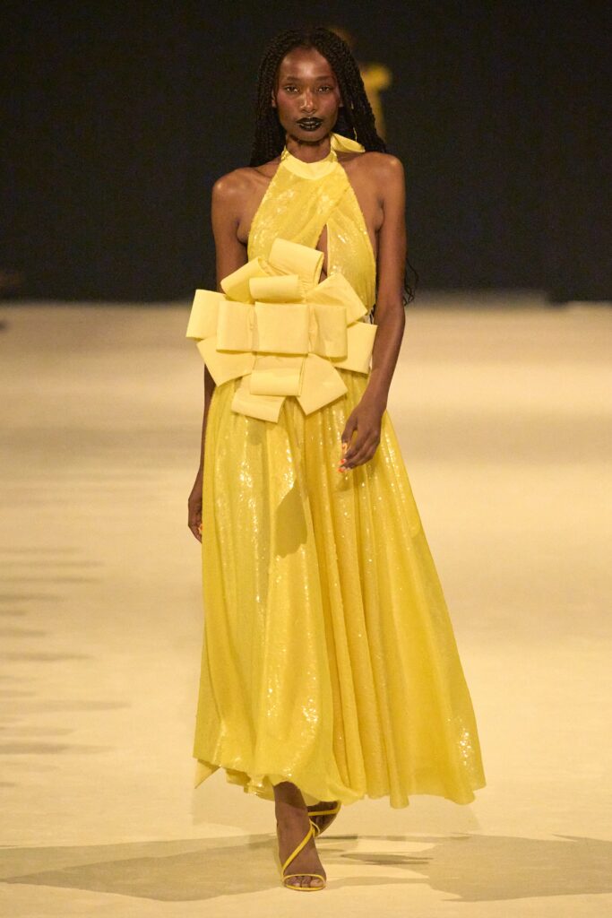 A relaxed yellow silk sleeveless dress with a halterneck and tiered design details.