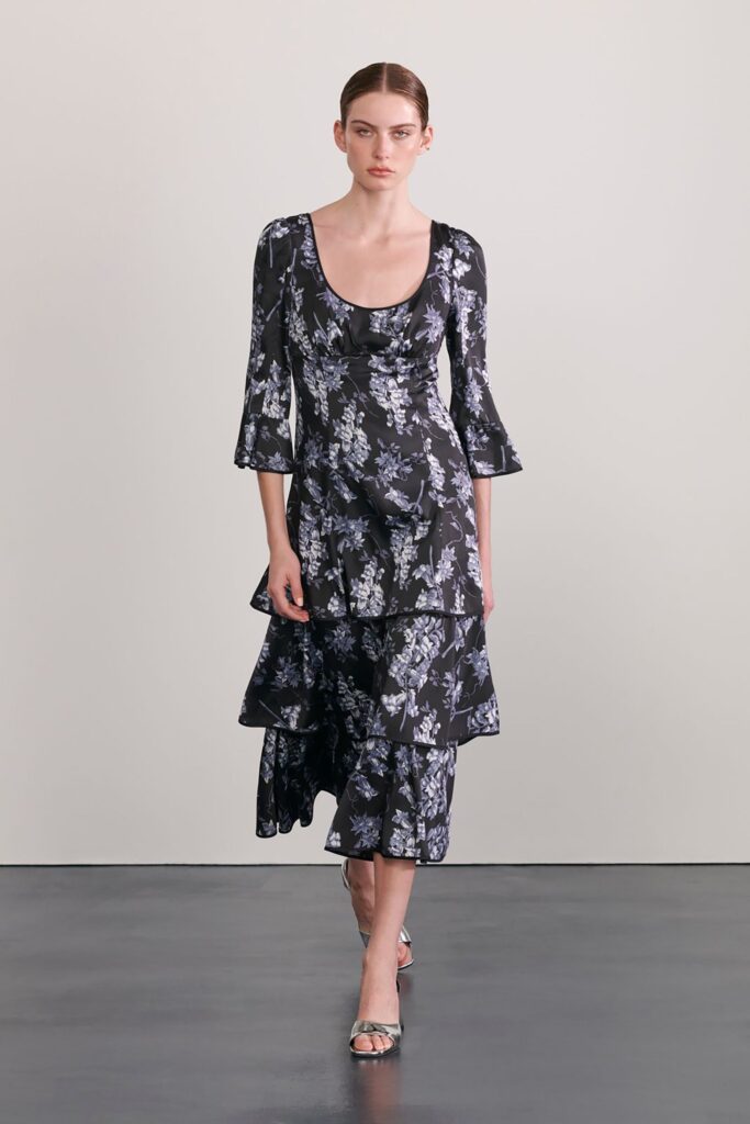 A fitted black cotton long-sleeve dress with a V-neckline and tiered design.