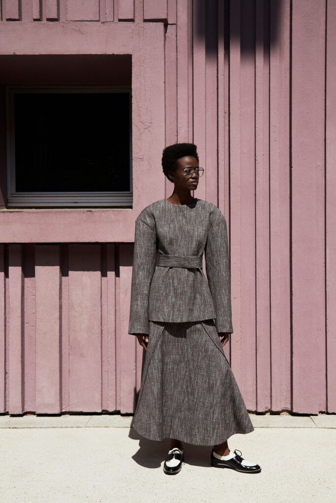 A fitted gray cotton dress with long sleeves and an asymmetric design detail.