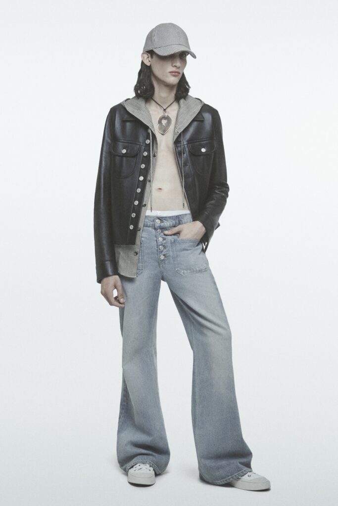 A relaxed black leather jacket with a collared neckline paired with wide-leg blue denim pants.