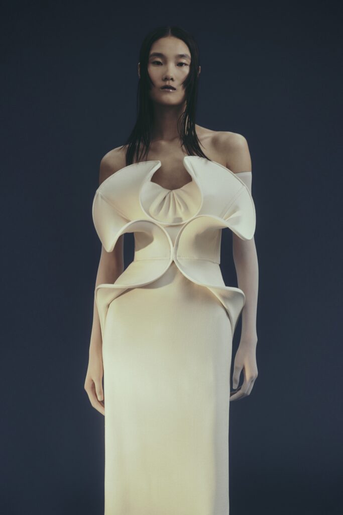 A fitted white silk dress with an off-shoulder design and asymmetric detailing.