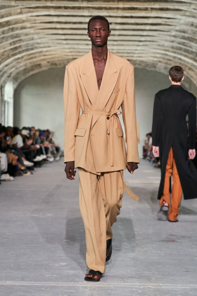 A relaxed beige blazer with matching trousers, featuring a belted design and long sleeves.