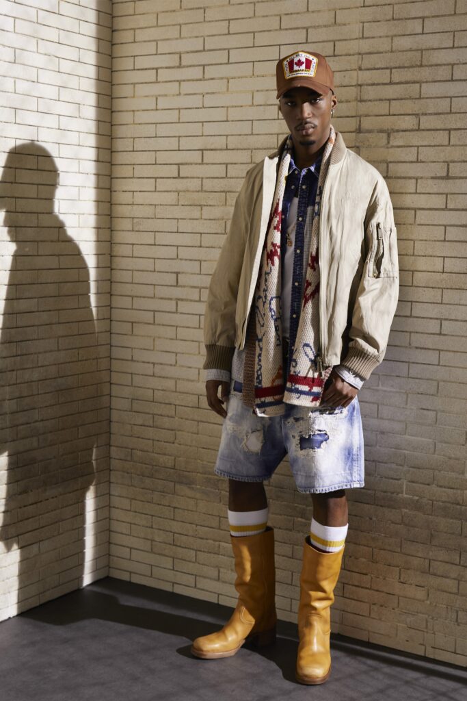 An oversized beige jacket paired with distressed blue denim shorts and yellow boots.