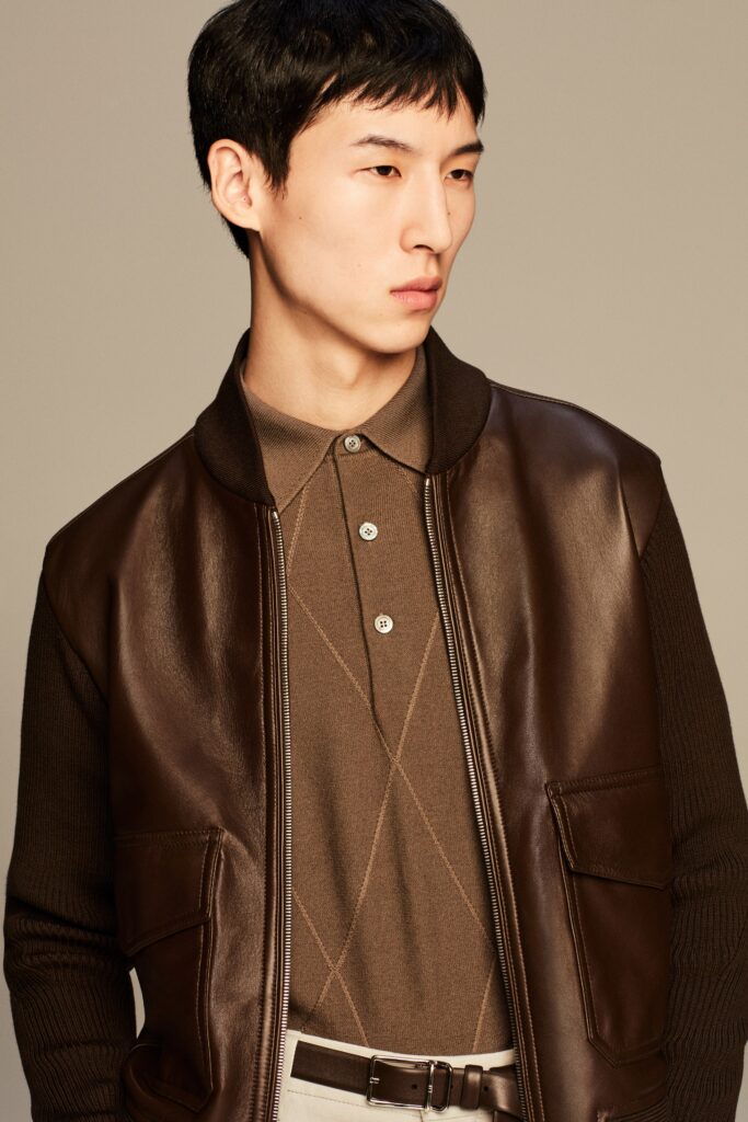 A fitted brown leather jacket with a collared neckline and buttoned front.