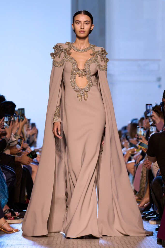 A fitted beige silk gown with long sleeves, high neckline, and intricate embroidery.