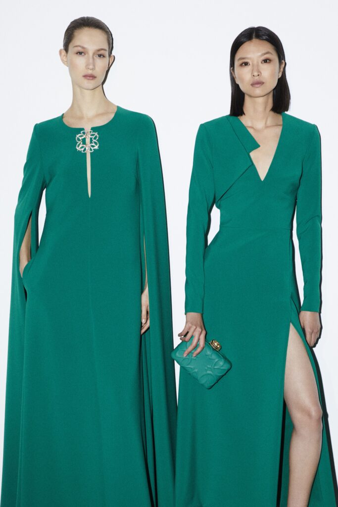 A fitted green silk dress with long sleeves and an asymmetric design featuring a V-neckline.