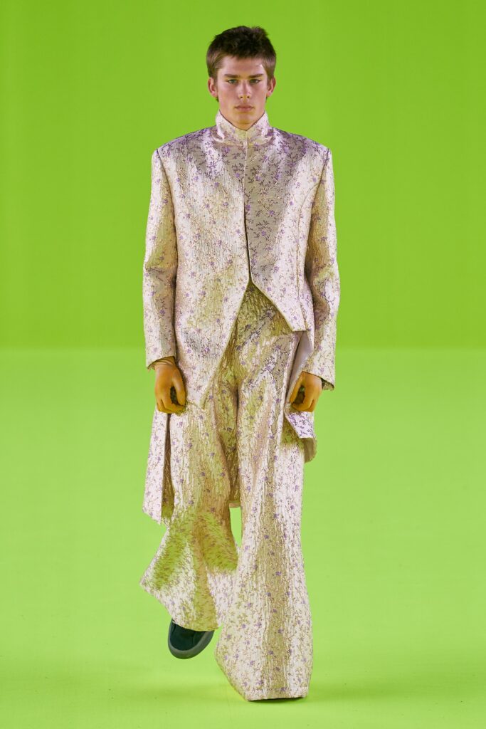 A tailored gold silk suit with long sleeves and an asymmetric design detail.