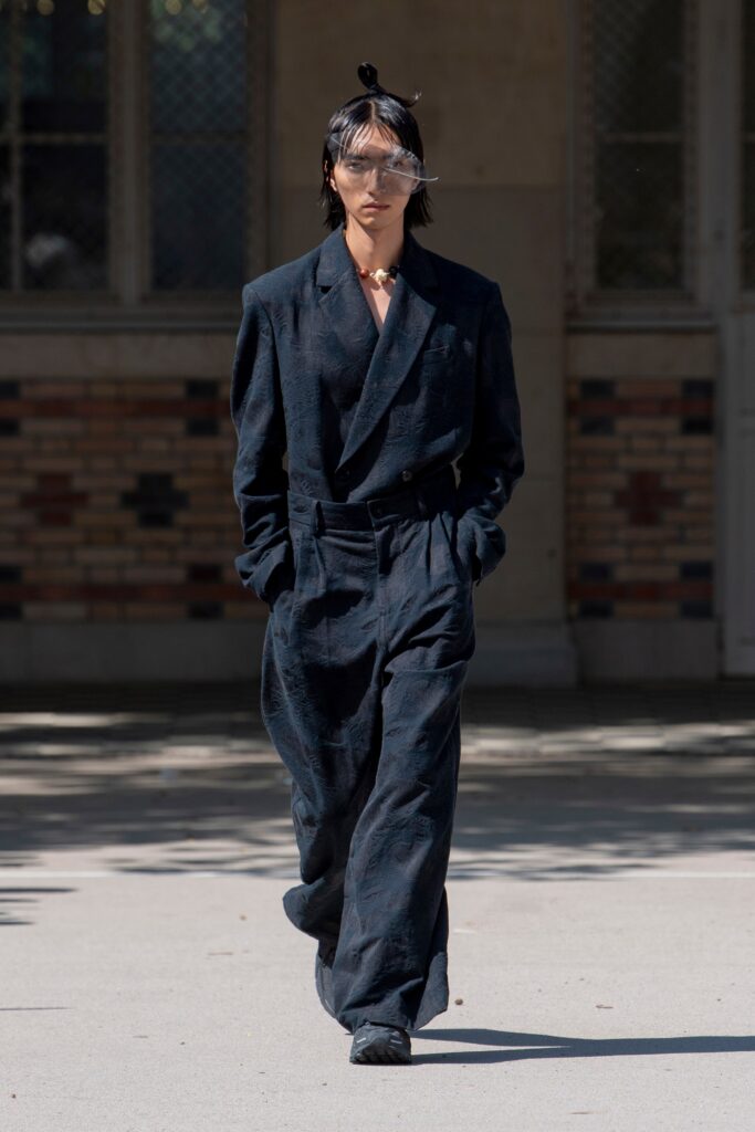 A relaxed black cotton suit with long sleeves and a collared design featuring wide-leg trousers.