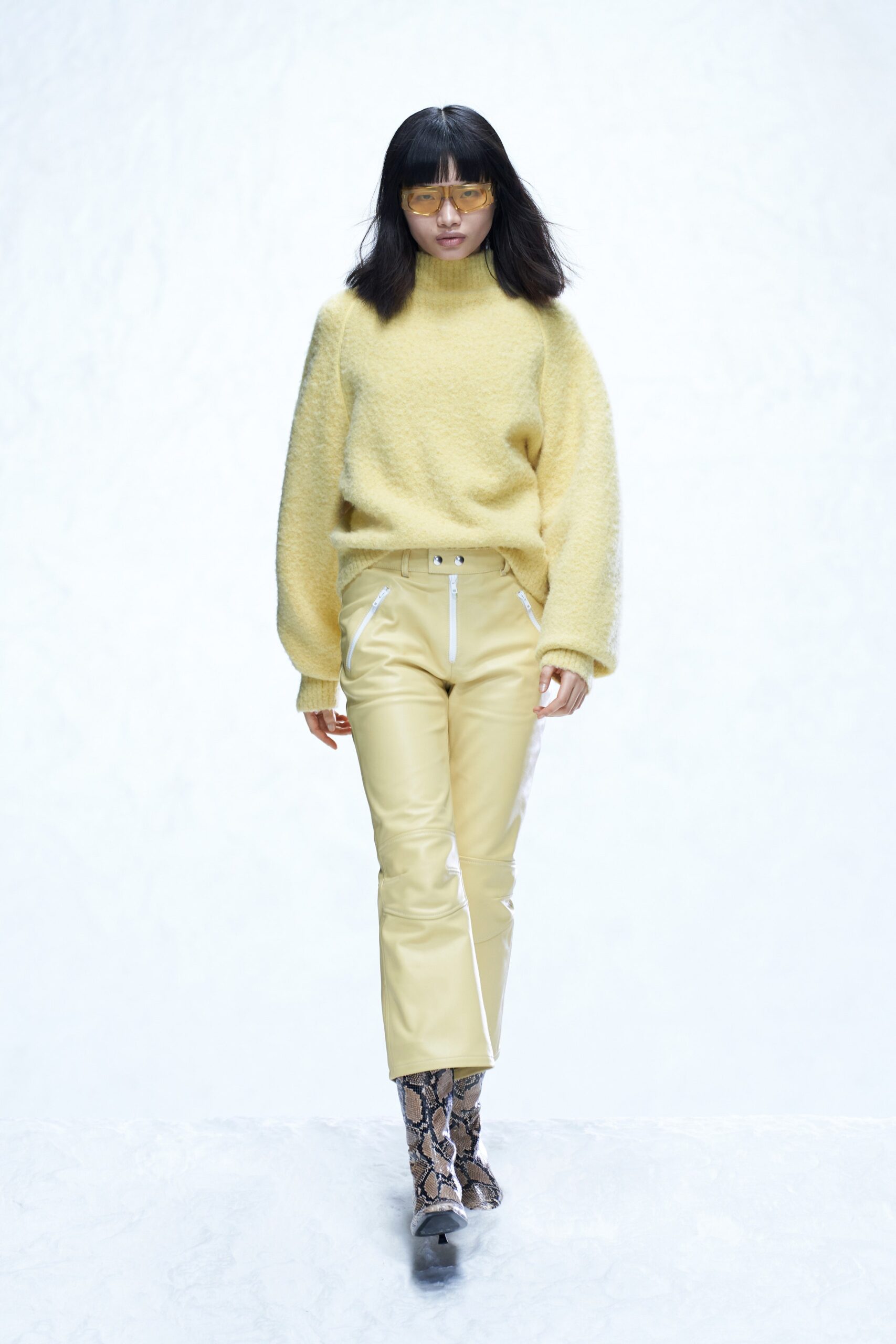 A relaxed yellow wool long-sleeve sweater paired with cream straight-leg leather pants.