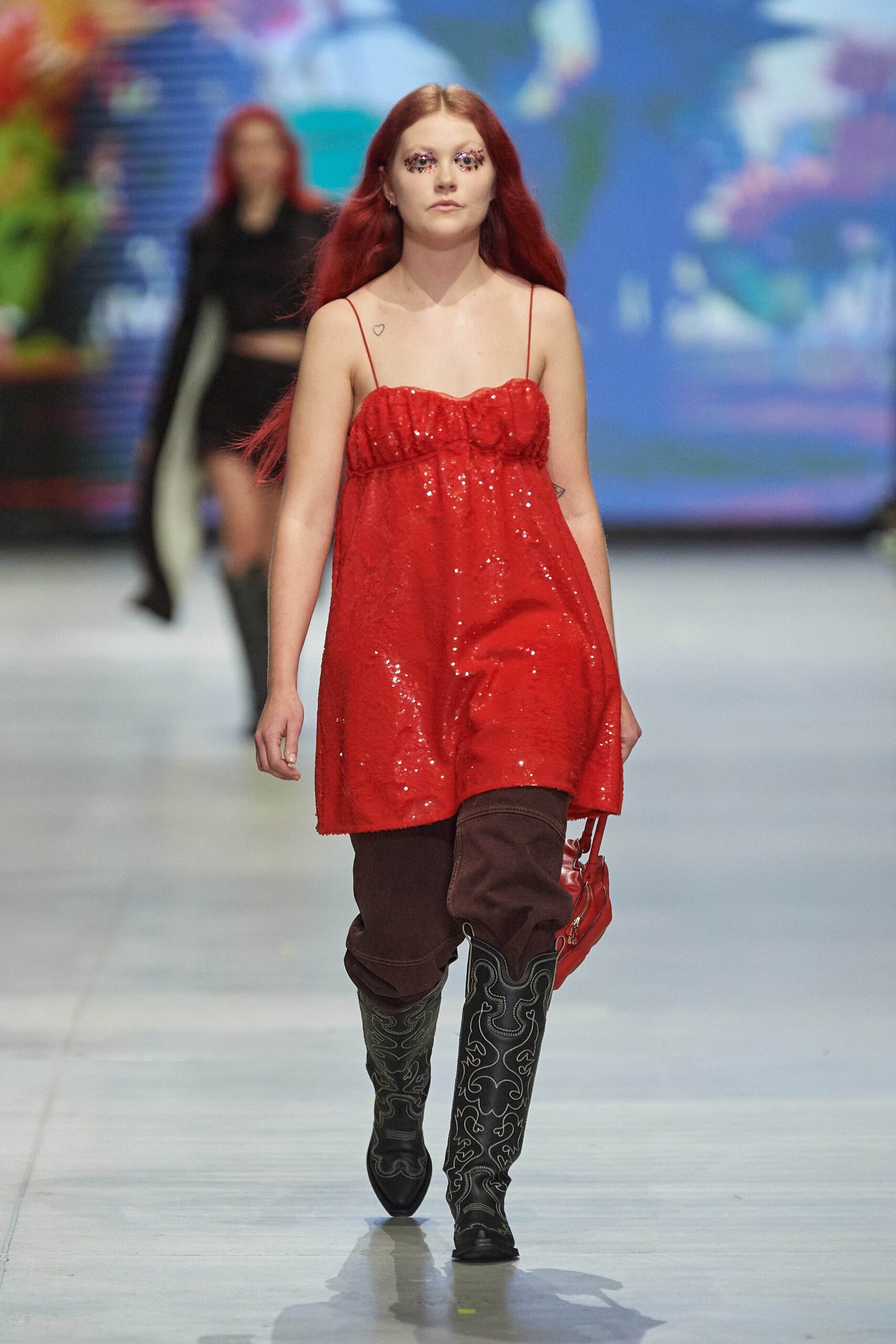 A fitted red sequin sleeveless dress paired with brown pants, featuring a tiered design.