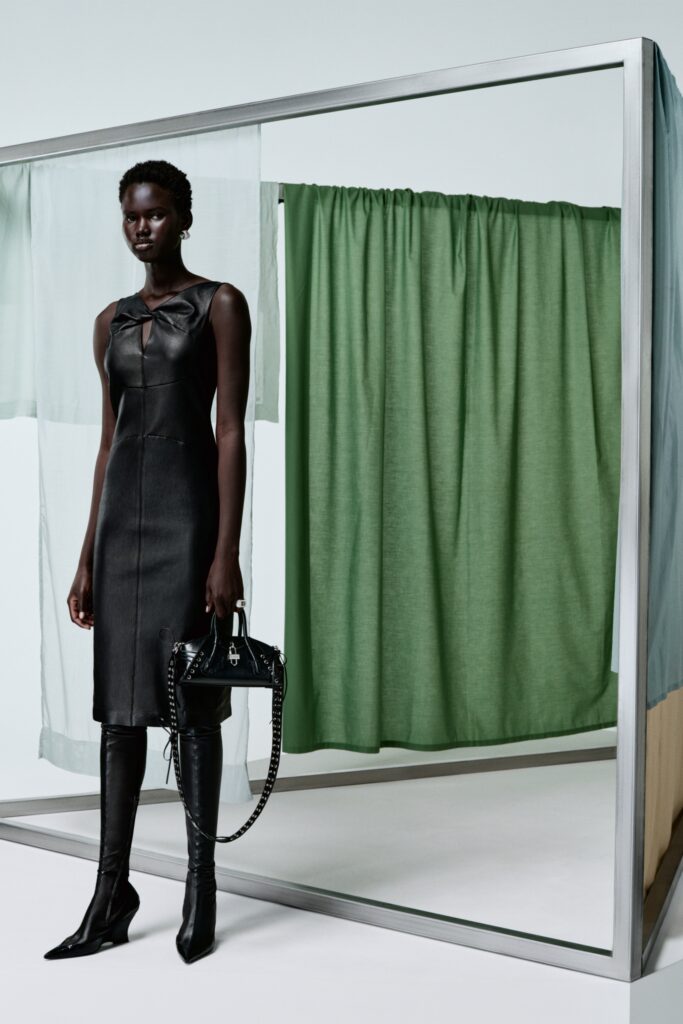 A fitted black leather sleeveless dress with a high neckline and straight-leg silhouette.