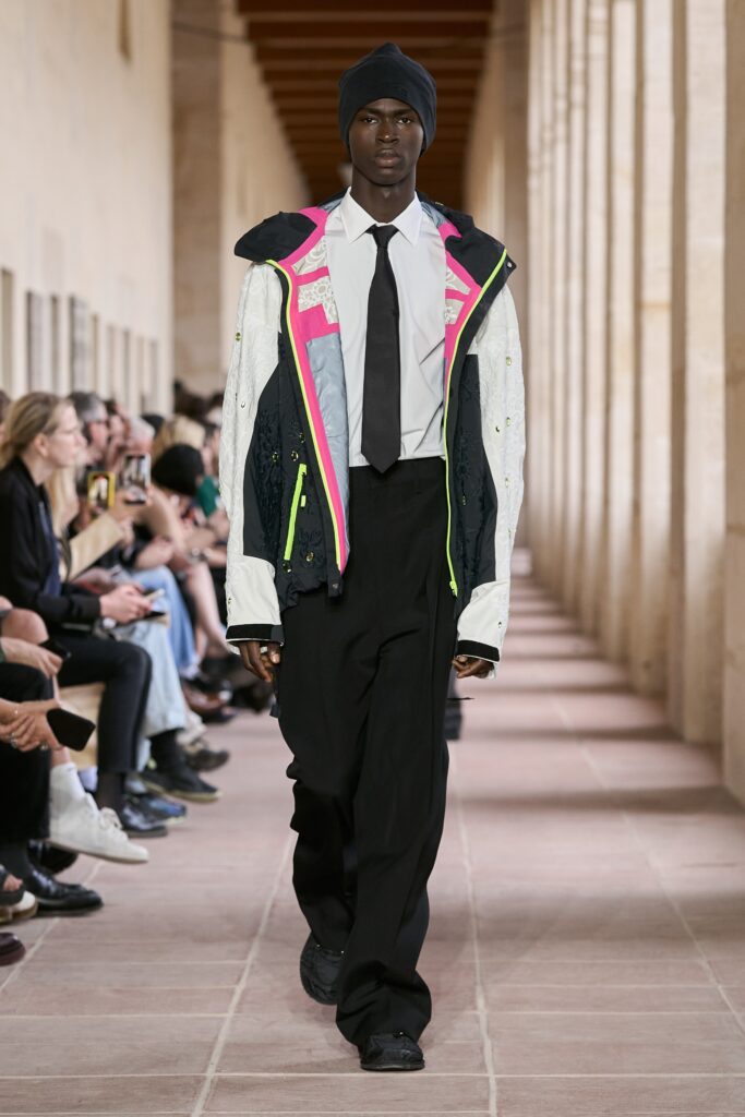 A relaxed-fit multicolor jacket paired with black pants, featuring a collared shirt underneath.