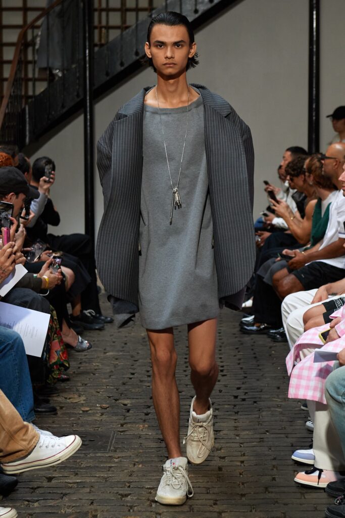 A relaxed gray dress paired with a long-sleeve collared jacket featuring an asymmetric design.