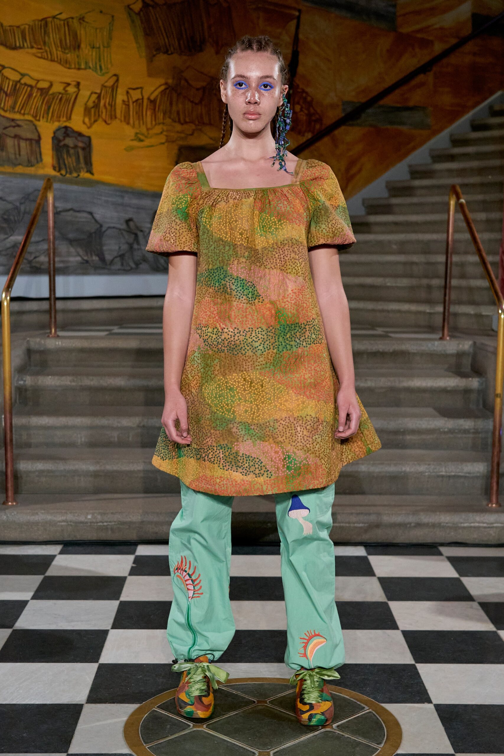 A relaxed green printed dress paired with colorful relaxed pants, creating a vibrant runway look.
