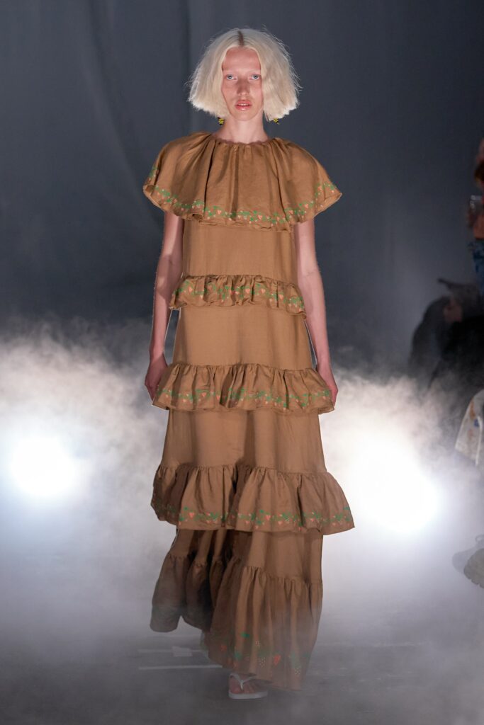 A relaxed brown cotton sleeveless dress with a high neckline and tiered design.