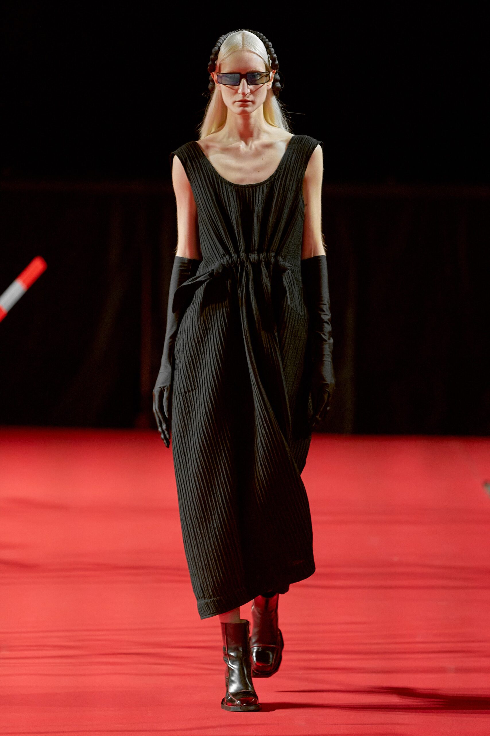 A relaxed black sleeveless dress with a high neckline and pleated design.