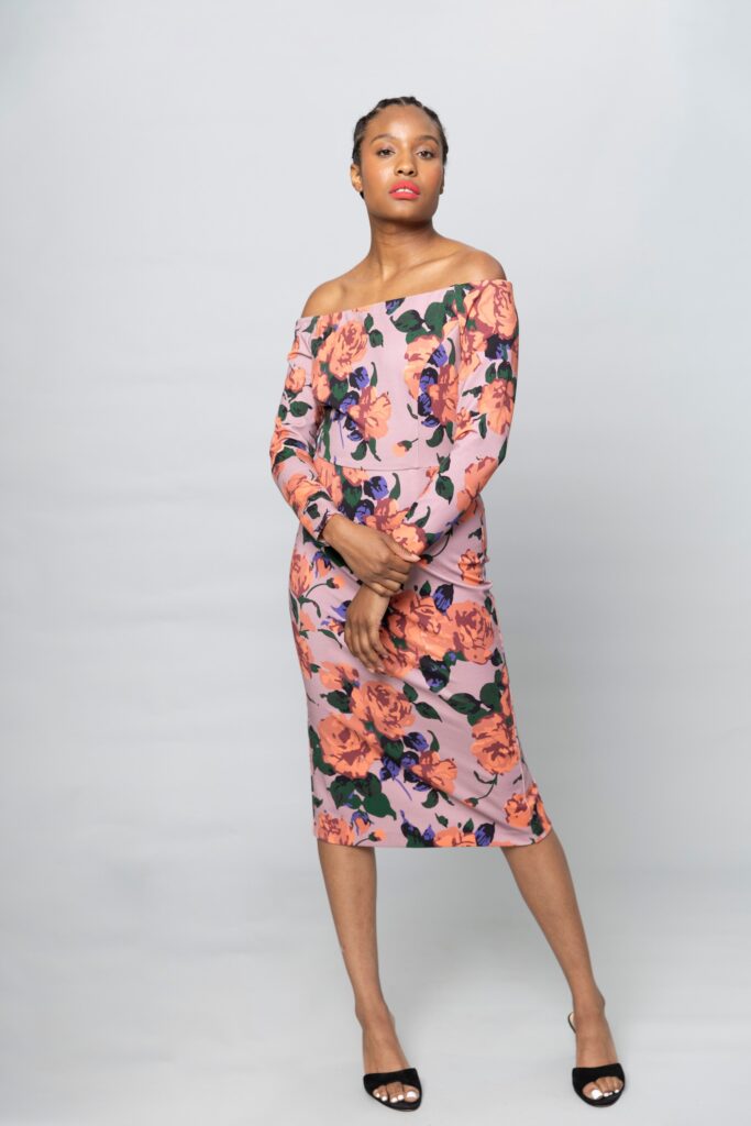 A fitted pink floral dress with long sleeves and an off-shoulder design.