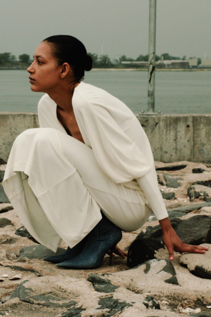 A fitted white silk sleeveless dress with a V-neckline and asymmetric design detail.