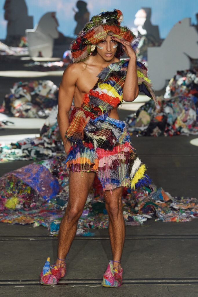A fitted multicolor sleeveless dress with an asymmetric design and fringed details.