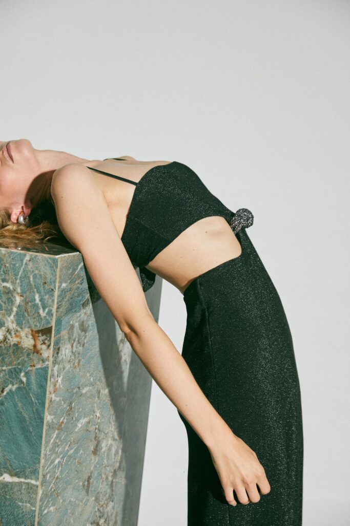 A fitted black silk dress featuring a sleeveless design with cutout details and a slit.