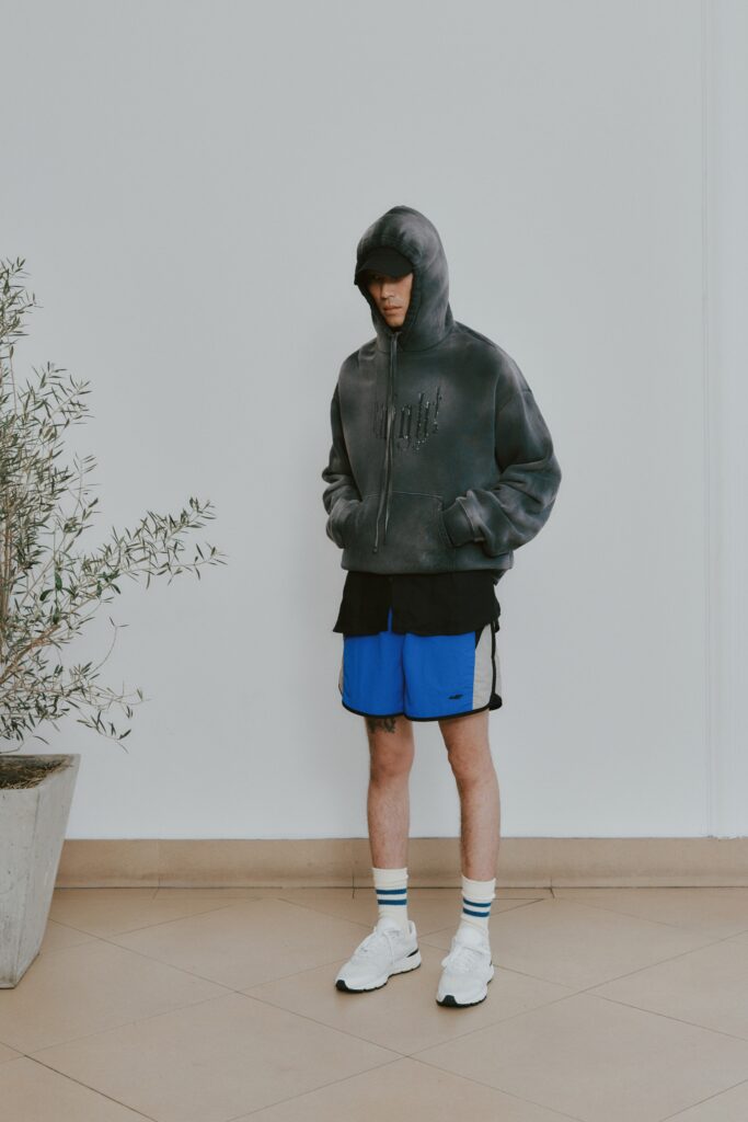 A relaxed black hoodie paired with blue shorts, featuring a layered look.