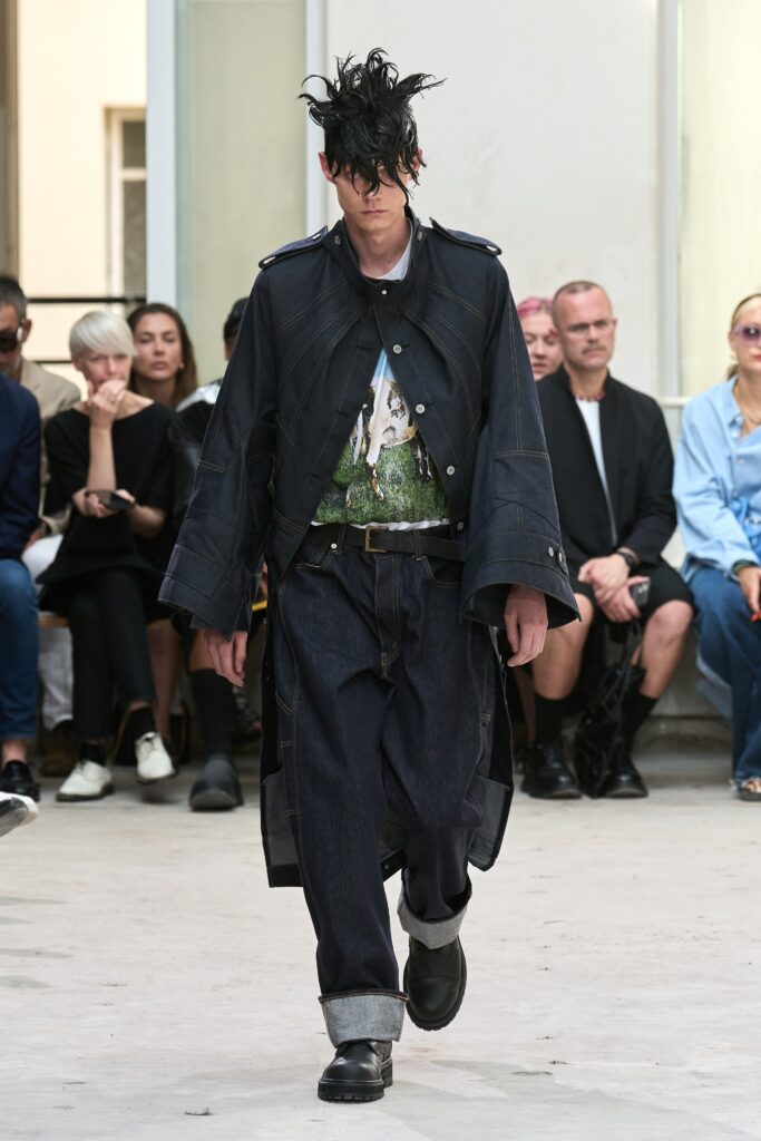 A relaxed black denim jacket with long sleeves paired with loose-fitting blue pants.