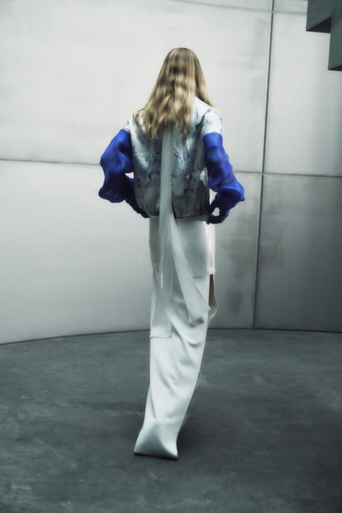 A fitted white silk dress with long sleeves and an asymmetric design detail.