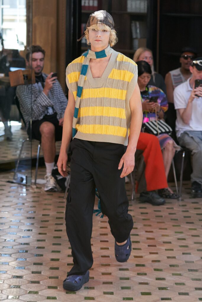 A relaxed yellow striped sweater with a V-neck paired with black pants.