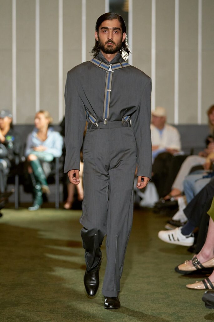 A fitted gray cotton jumpsuit with long sleeves, a collared neckline, and an asymmetric design.