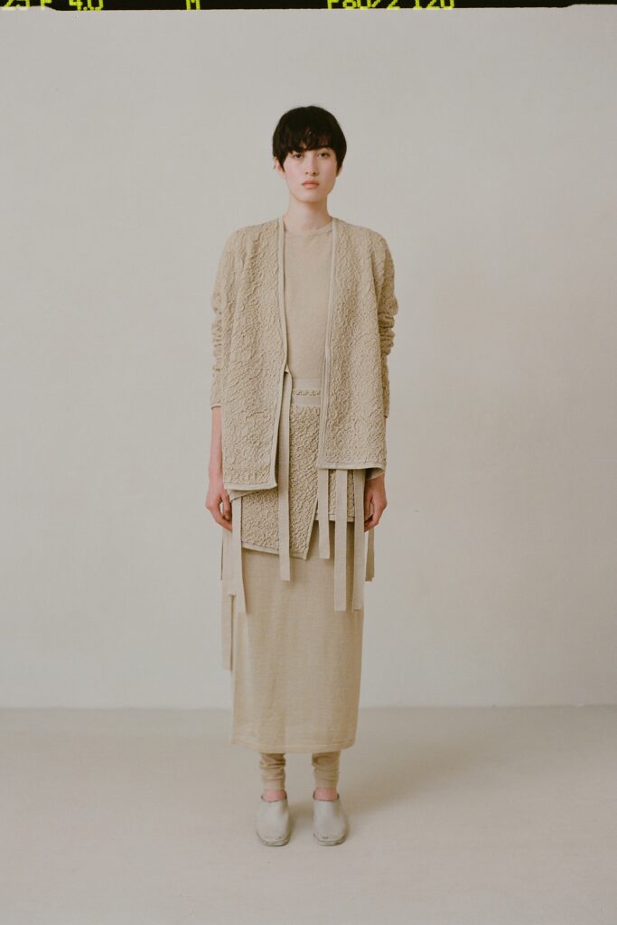 A relaxed beige dress layered with a long-sleeve collared jacket.
