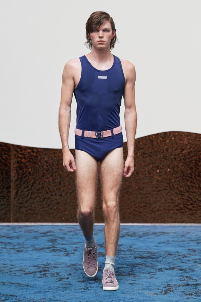 A fitted blue neoprene swimsuit with a sleeveless design and high-neck construction featuring color-blocked details.