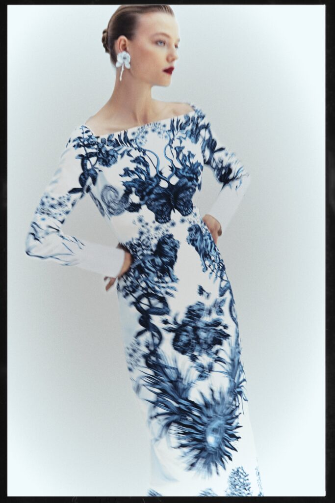 A fitted white and blue printed dress with long sleeves and an off-shoulder design.