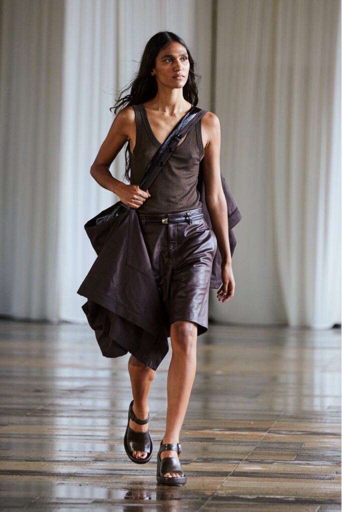 A relaxed brown sleeveless top paired with brown leather shorts featuring an asymmetric design.