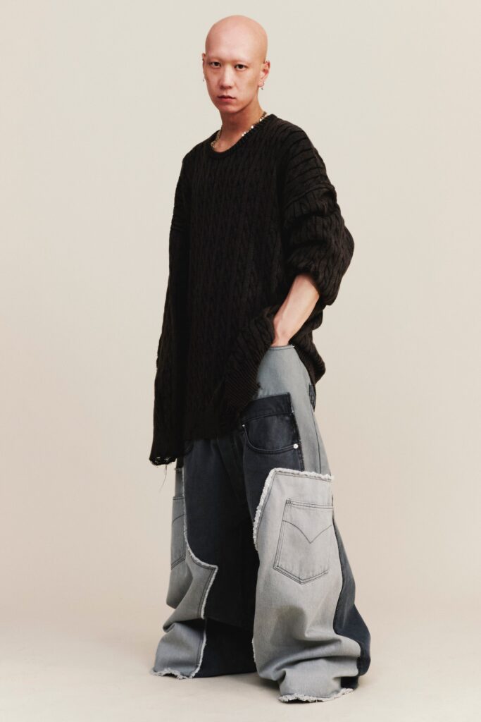An oversized black sweater paired with wide-leg blue denim pants for a relaxed look.