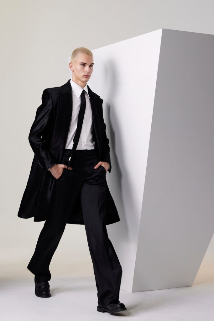 A fitted black silk coat with long sleeves and a collared neckline paired with straight-leg pants.