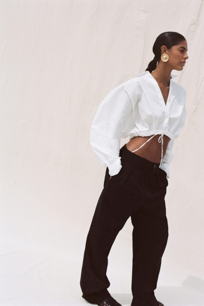 A relaxed white long-sleeve cropped top paired with black relaxed-fit pants.