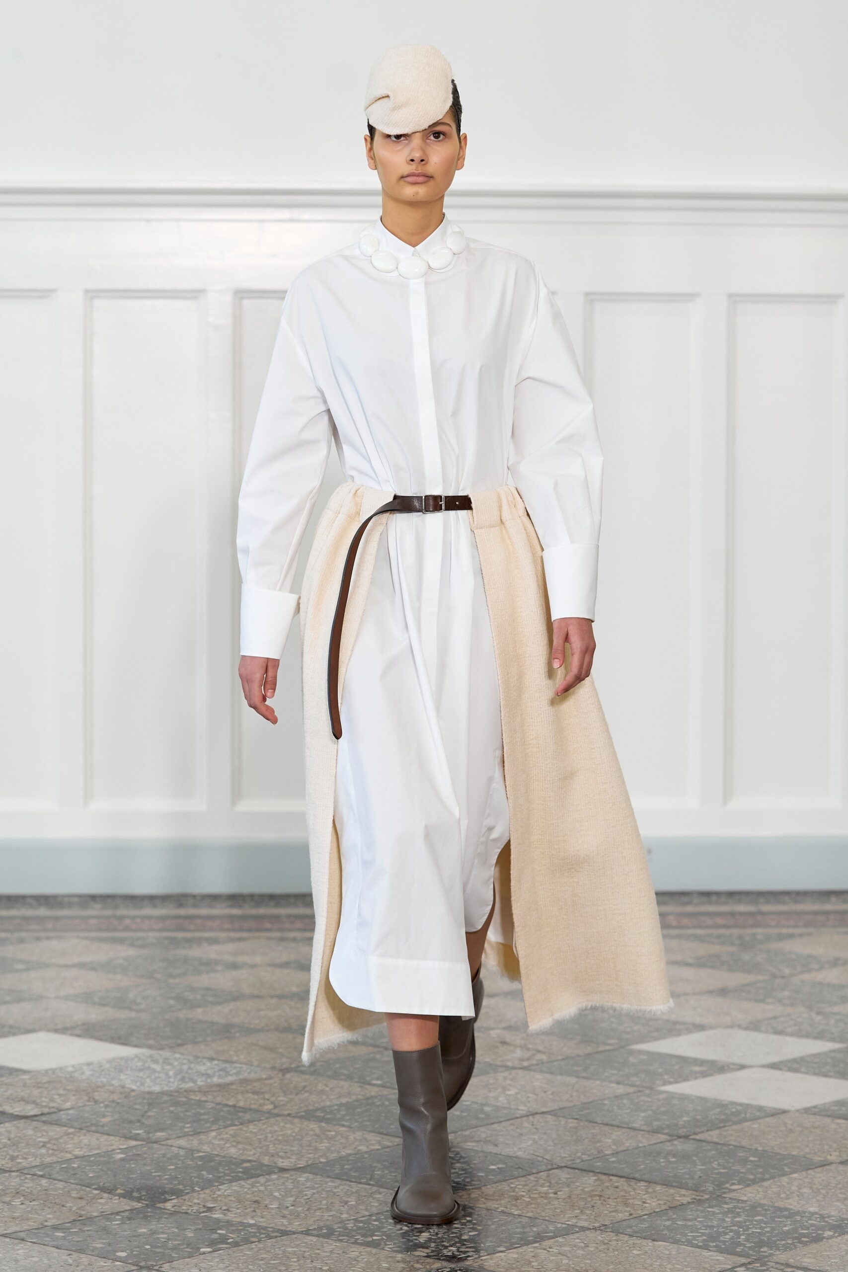 A relaxed white cotton dress with long sleeves, a collared neckline, and tiered design details.