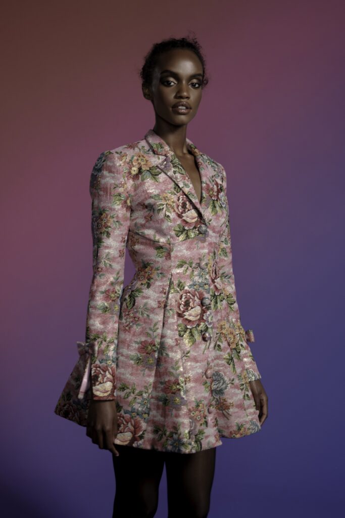 A fitted pink silk dress with long sleeves, a collared neckline, and a flared silhouette.
