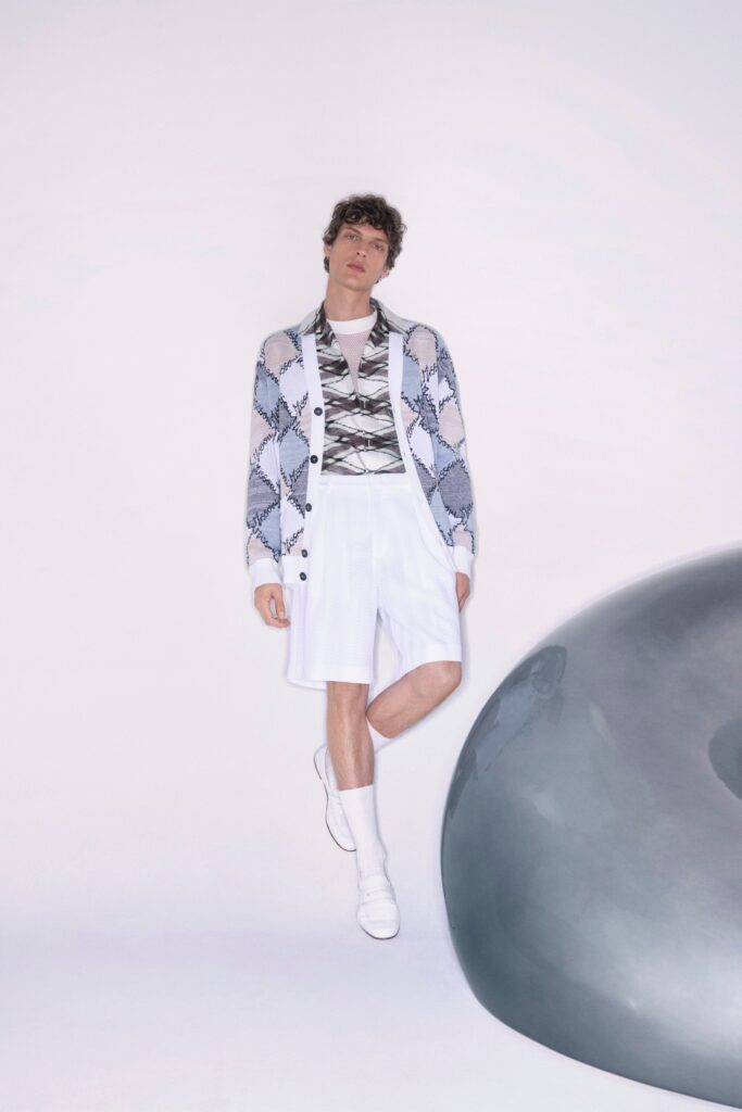 A relaxed white cardigan with long sleeves paired with gray shorts, featuring a layered look.