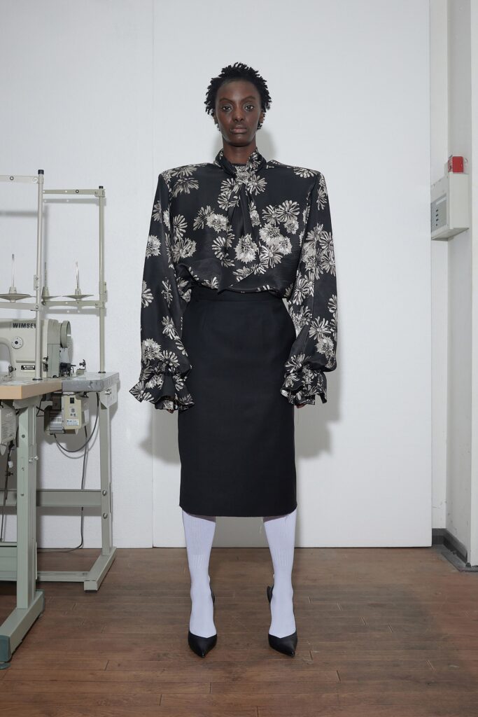 A fitted black and white floral blouse with long sleeves and a flared skirt.