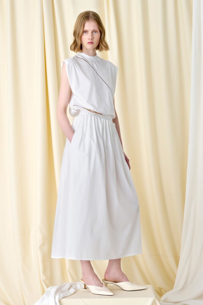 A relaxed white sleeveless dress with a high neckline and tiered design.