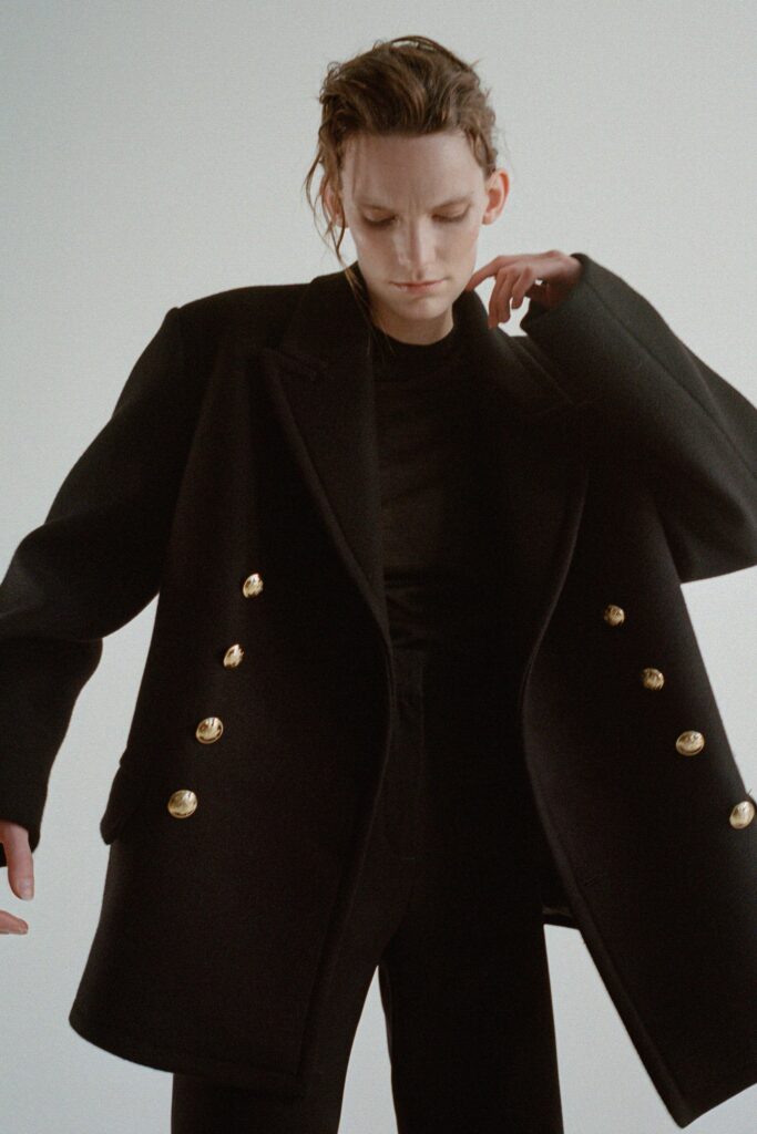 An oversized black wool coat with long sleeves and button detailing.