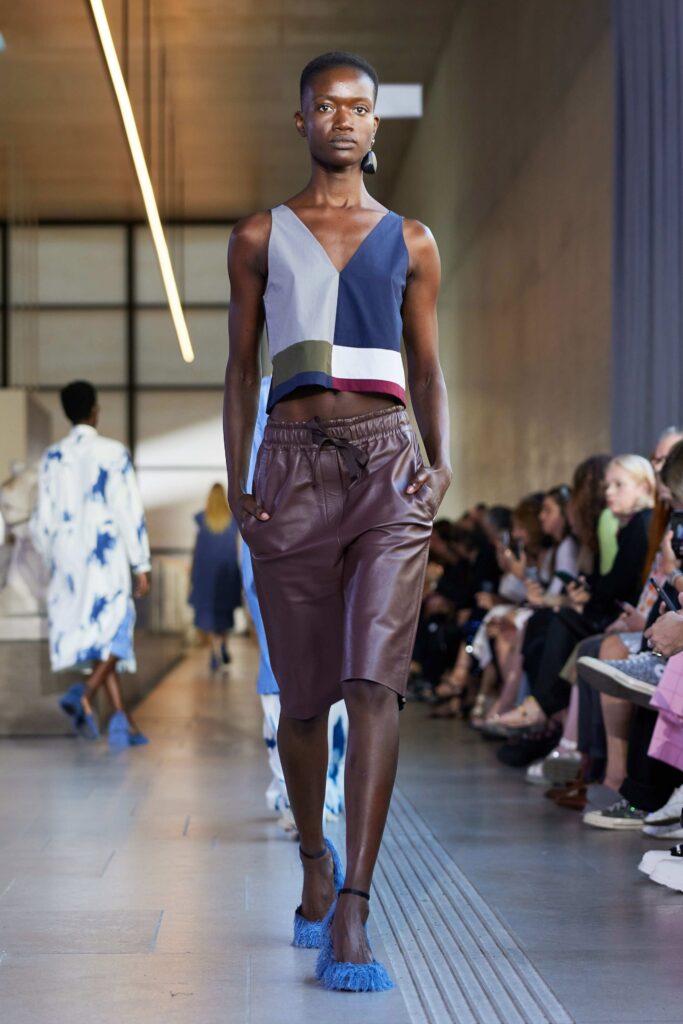 A fitted cropped top in blue paired with brown leather shorts, perfect for a stylish summer look.