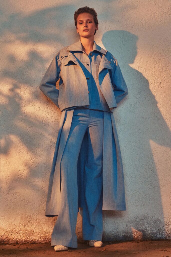 A relaxed blue denim jacket with long sleeves and a collared neckline paired with wide-leg pants.