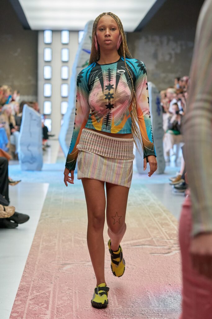 A fitted multicolor long-sleeve top with a high-neck paired with a pleated skirt.