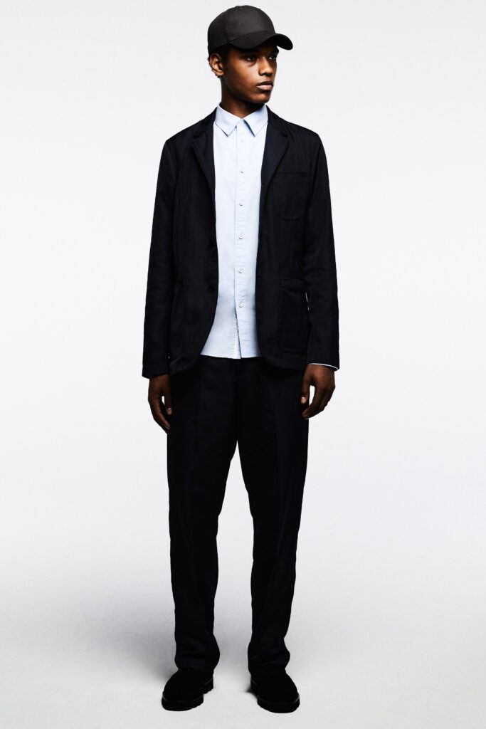 A relaxed black jacket layered over a collared blue shirt, featuring buttoned details.