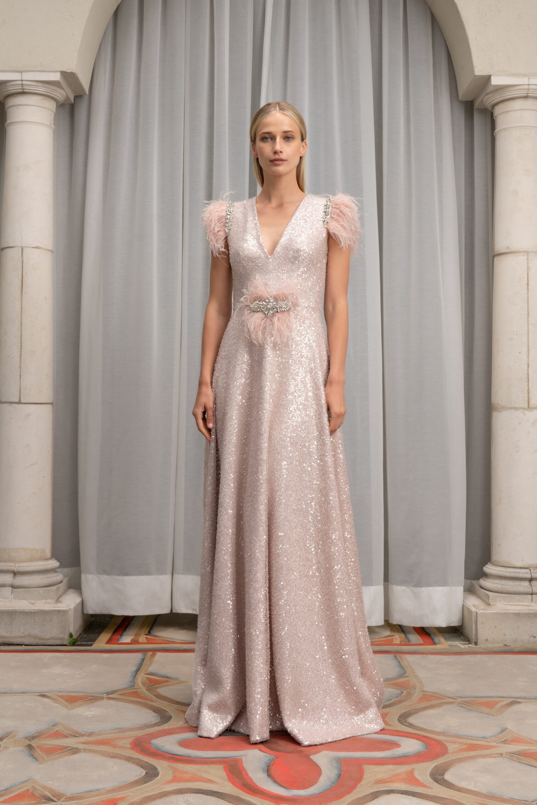 A fitted pink sequin gown with a V-neckline and tiered design details.