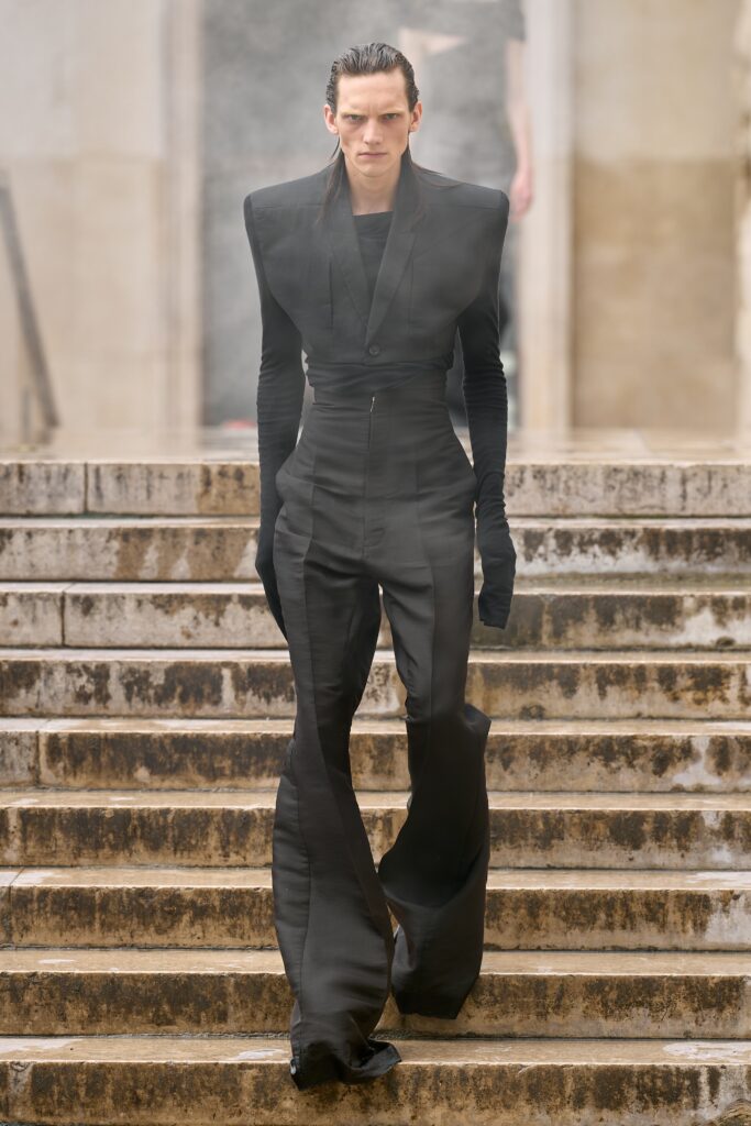 A fitted black silk jumpsuit with long sleeves and a V-neckline featuring a flared silhouette.