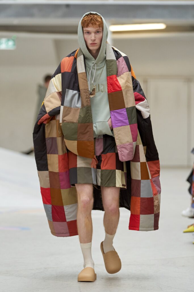 An oversized multicolor coat with a hood paired with checked shorts.